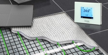 Cross-section of electric underfloor heating mat installed under dark floor tiles with Devex TS-500 thermostat