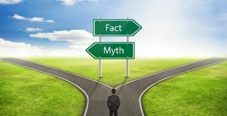Person standing at a crossroads with Fact and Myth road signs, representing common underfloor heating myths vs facts