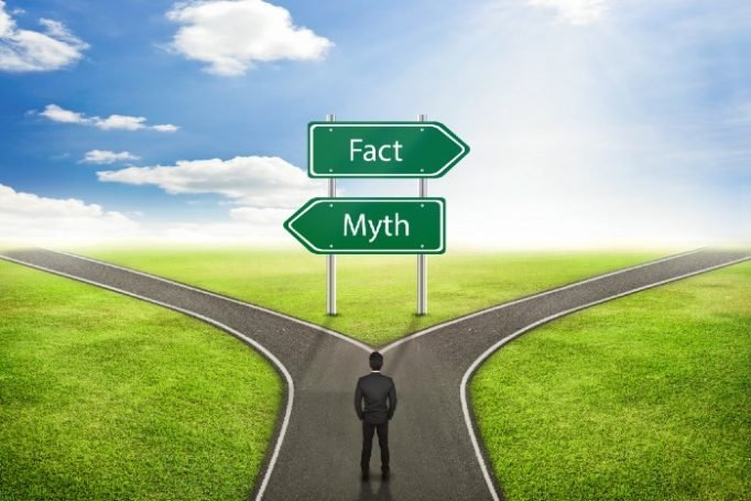 Person standing at a crossroads with Fact and Myth road signs, representing common underfloor heating myths vs facts