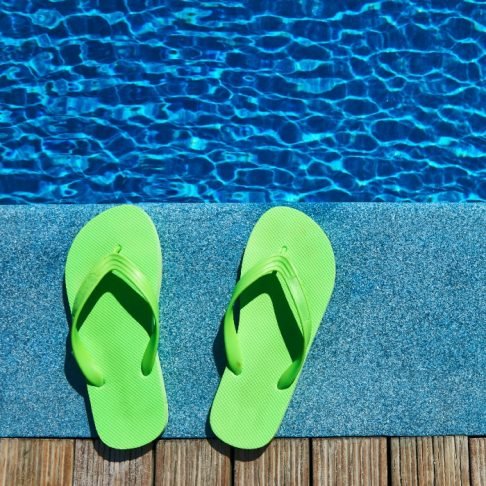 Green thongs beside a swimming pool on a warm summer day, illustrating outdoor and poolside heating comfort