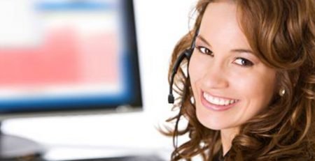 Smiling customer service representative wearing headset at computer workstation