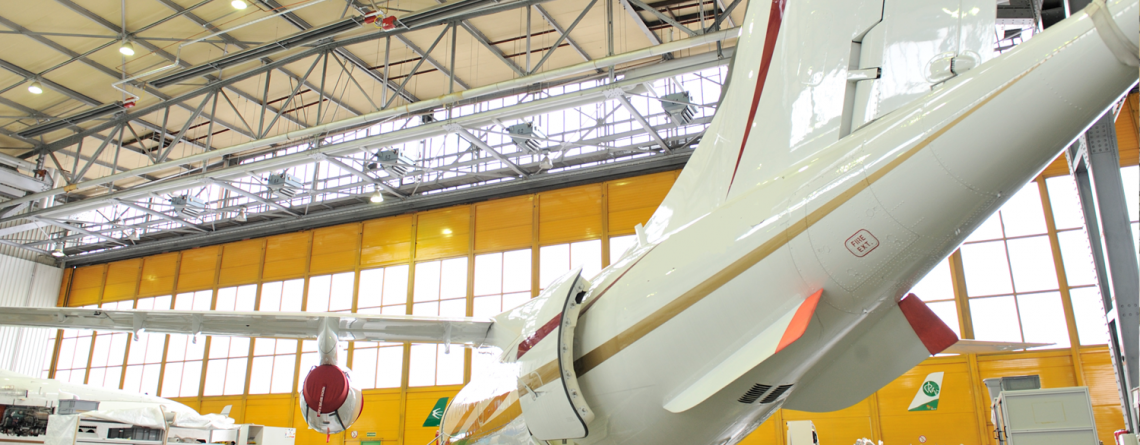 Schwank gas tube heaters installed in large aircraft hangar ceiling with commercial jet inside