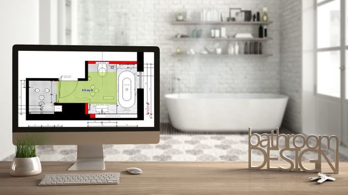 Computer displaying a bathroom floor plan with bathroom design lettering, in a modern Scandinavian bathroom