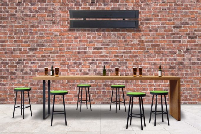 Comfortline infrared heater mounted above a pub bar area with exposed brick wall and green stools