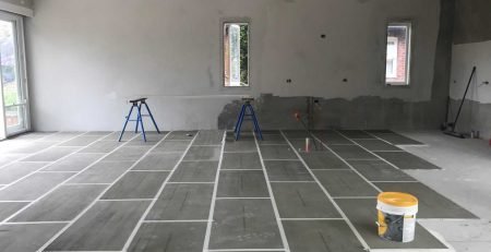 Underfloor heating installation in progress with heating cables laid in a grid pattern across a concrete subfloor