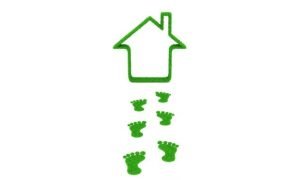 Eco-friendly home concept with green footprints leading to a grass house outline